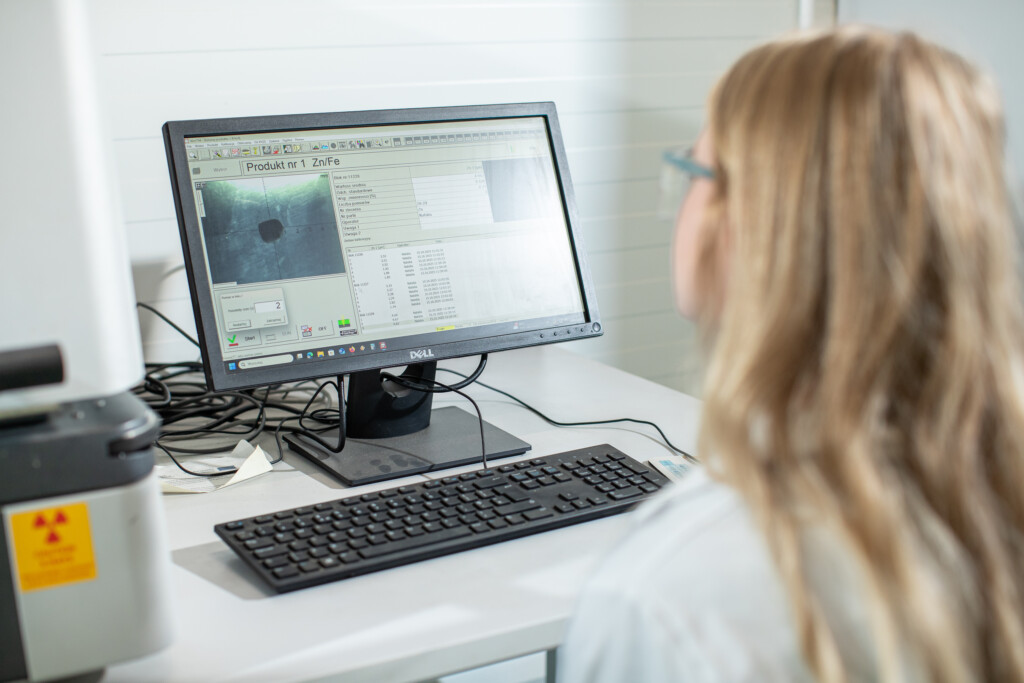 Kobieta w okularach pracuje przy komputerze, analizując dane na ekranie w laboratorium technicznym