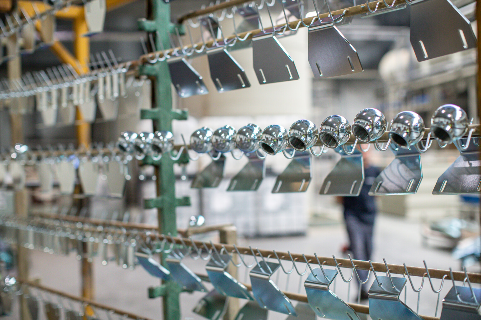 Metalowe elementy konstrukcyjne i akcesoria zawieszone na stelażu w halach produkcyjnych firmy LEANN